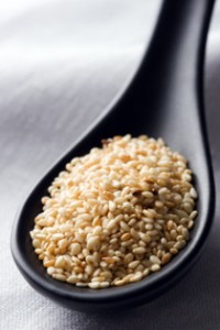 Sesame seeds on a black spoon.